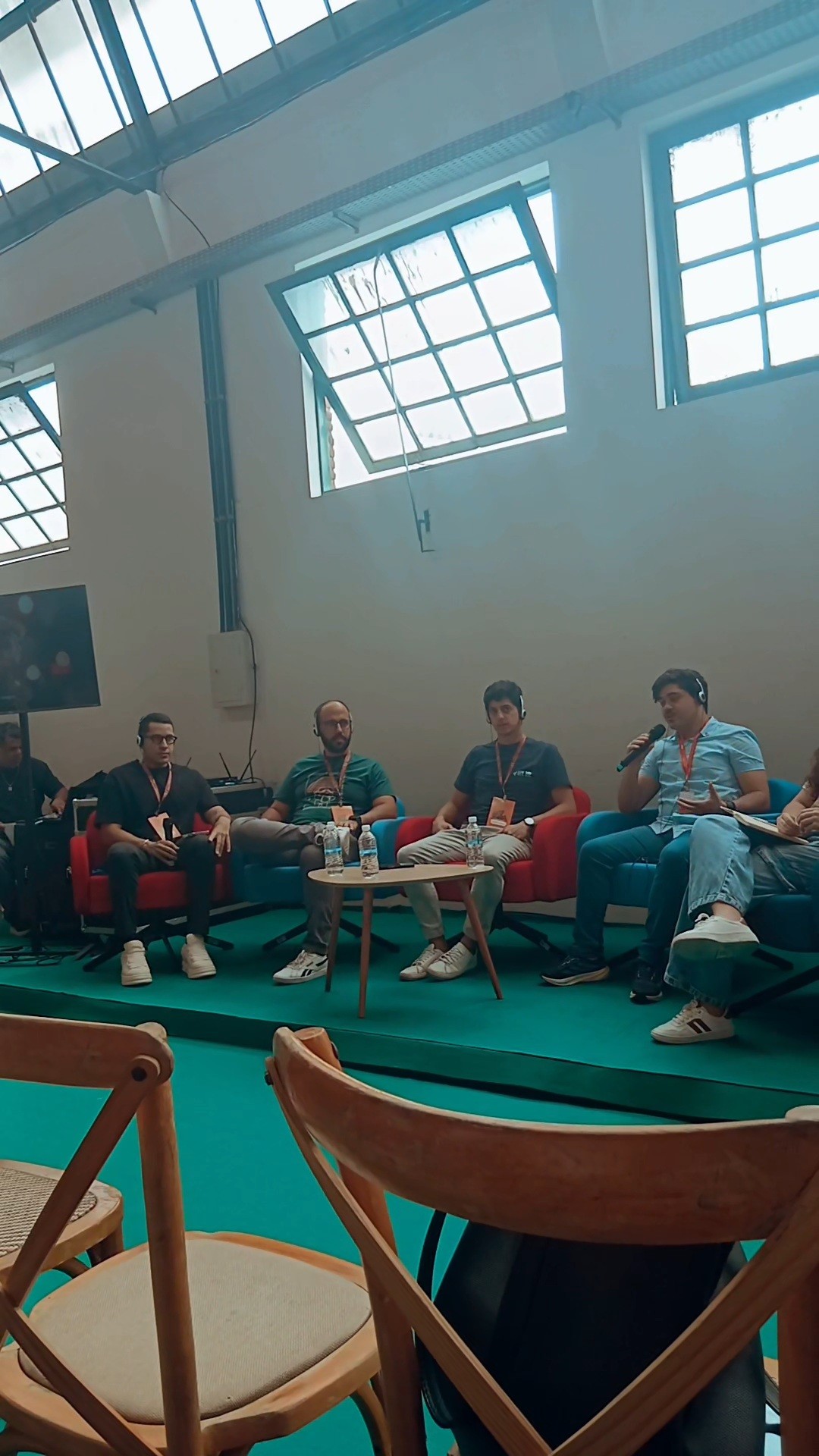 Participantes de uma mesa no Rolê REC'n'Play; uma pessoa fala ao microfone